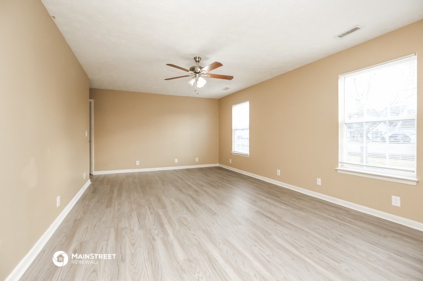 the spacious living room with hardwood floors and a ceiling fan