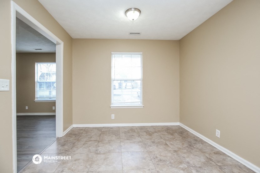 the spacious living room of an empty home with a large window