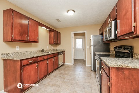 a kitchen with wooden cabinets and granite counter tops and a refrigerator