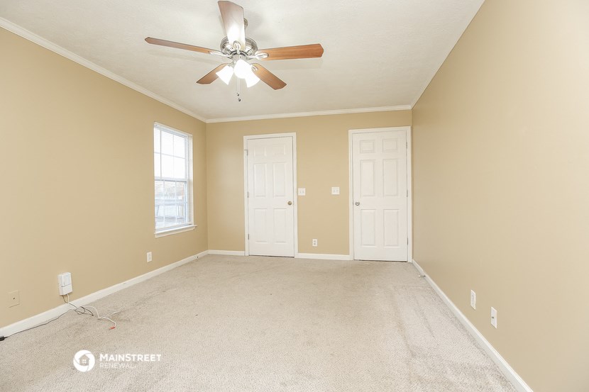 the master bedroom has a carpeted floor and a ceiling fan