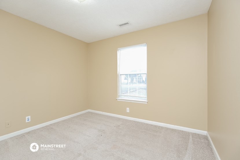 an empty room with a window and carpet
