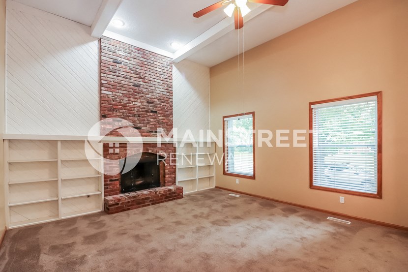 a living room with a brick fireplace and a carpeted floor