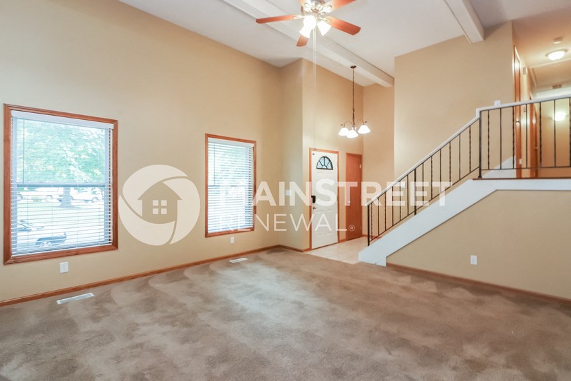 a large living room with a staircase and a large window