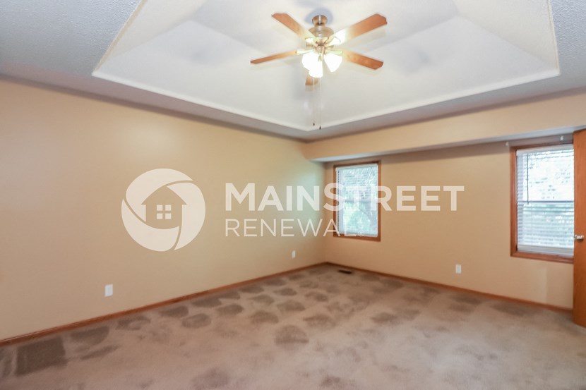 a large living room with a ceiling fan and a carpeted floor