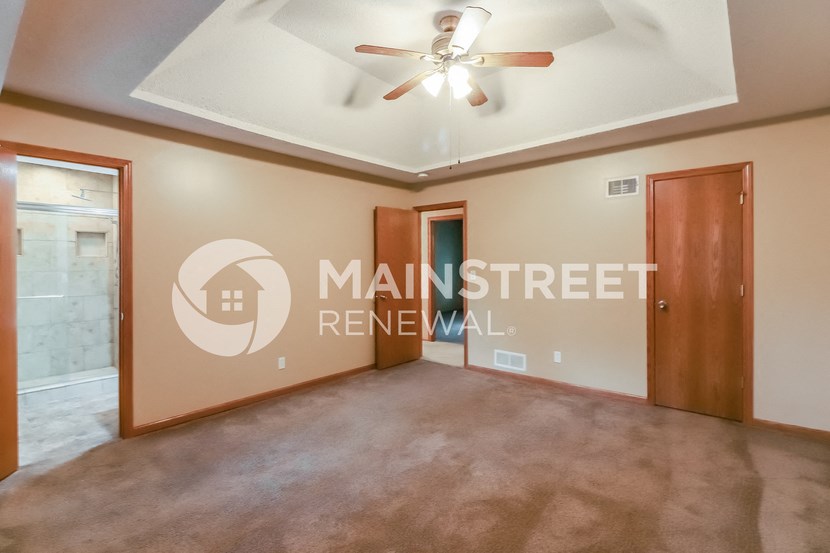 a living room with a ceiling fan and a door to a bathroom