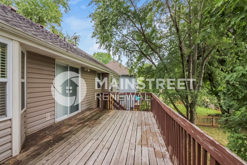 a large deck on the side of a house with trees