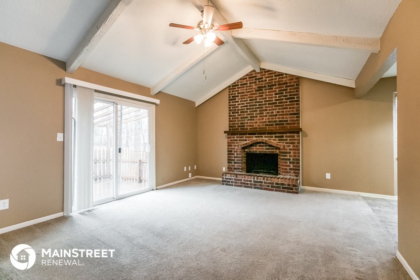 an empty living room with a fireplace and a ceiling fan