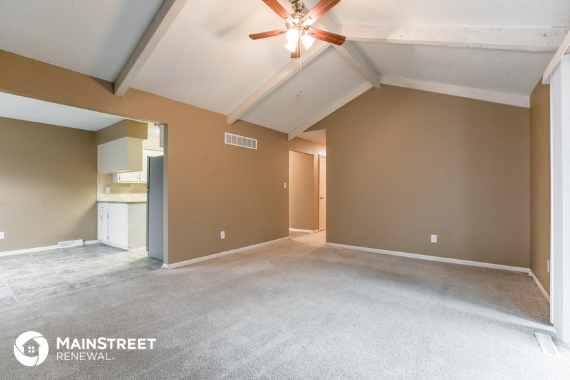 the living room and dining room of an empty house with a ceiling fan