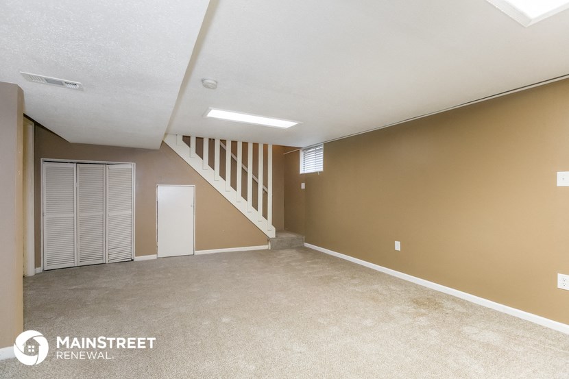 an empty living room with a white door and a staircase