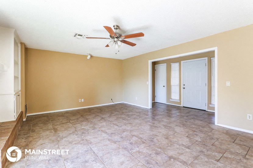 an empty living room with a ceiling fan and tile floor