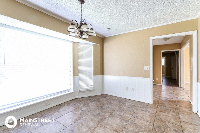 an empty living room with a large window and tile floor