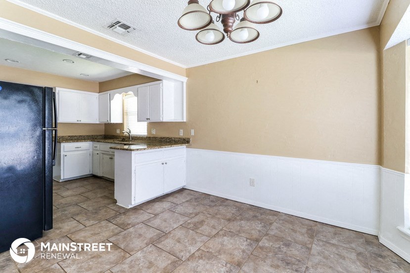 a kitchen with white cabinets and a sink and a refrigerator