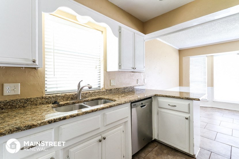 a kitchen with white cabinets and granite counter tops and a sink