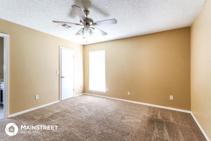 a living room with carpet and a ceiling fan