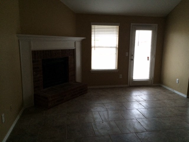an empty living room with a fireplace and tiled floors