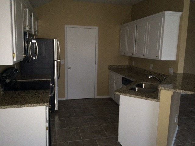 a kitchen with white cabinets and a sink and a refrigerator