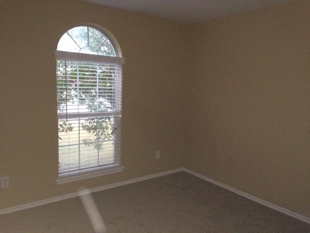 an empty living room with a window and blinds