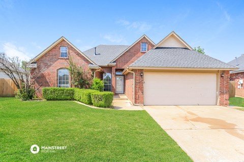 a brick house with a garage and a lawn