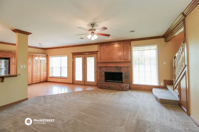 an empty living room with a fireplace and a ceiling fan
