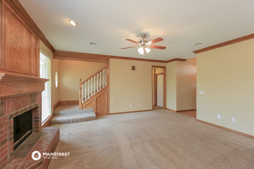a empty living room with a fireplace and a ceiling fan