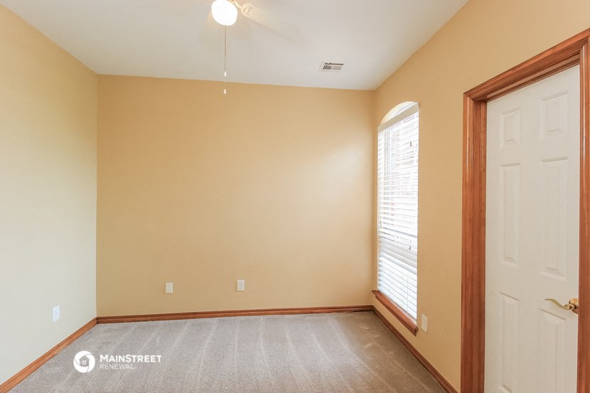 an empty living room with a white door and a window