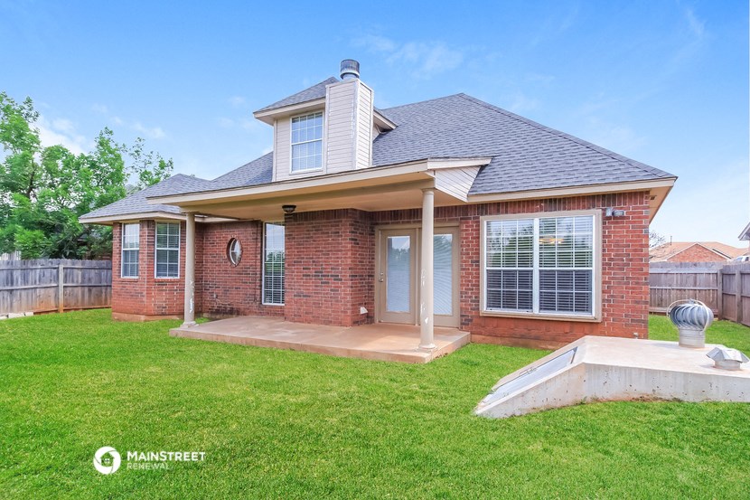 a brick house with a porch and a pool in the grass