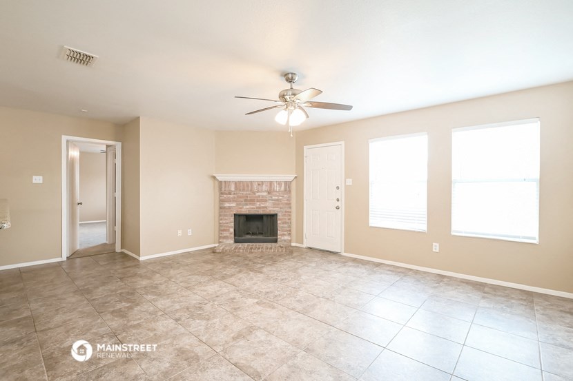 an empty living room with a fireplace and a ceiling fan