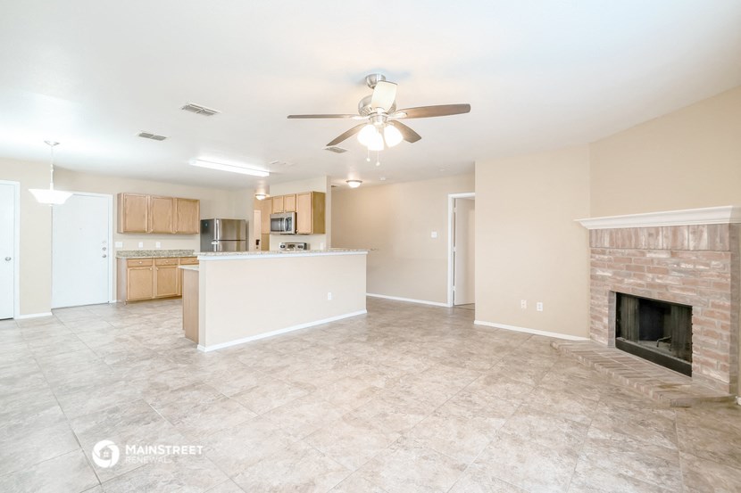 an empty living room with a fireplace and a kitchen
