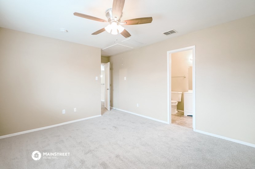 an empty living room with a ceiling fan and a bathroom