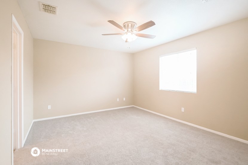 an empty room with a ceiling fan and a window