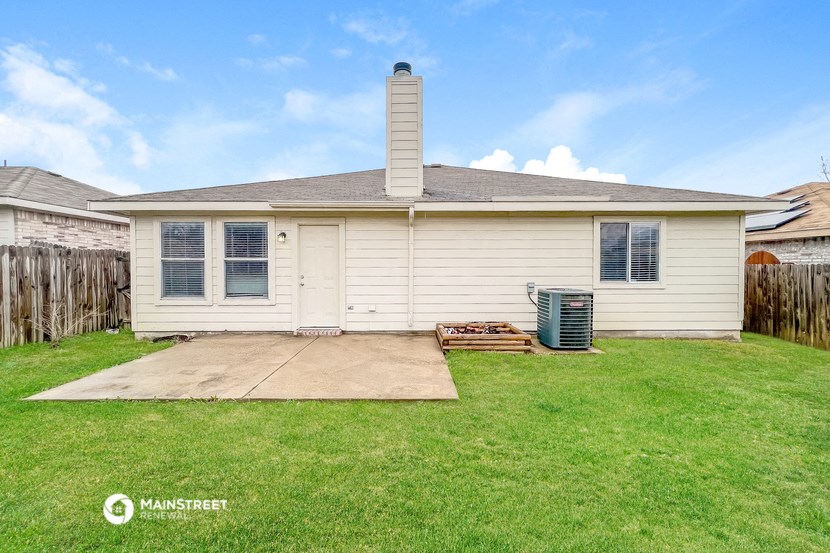 a small white house with a yard and a backdoor