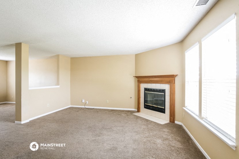 an empty living room with a fireplace and large windows