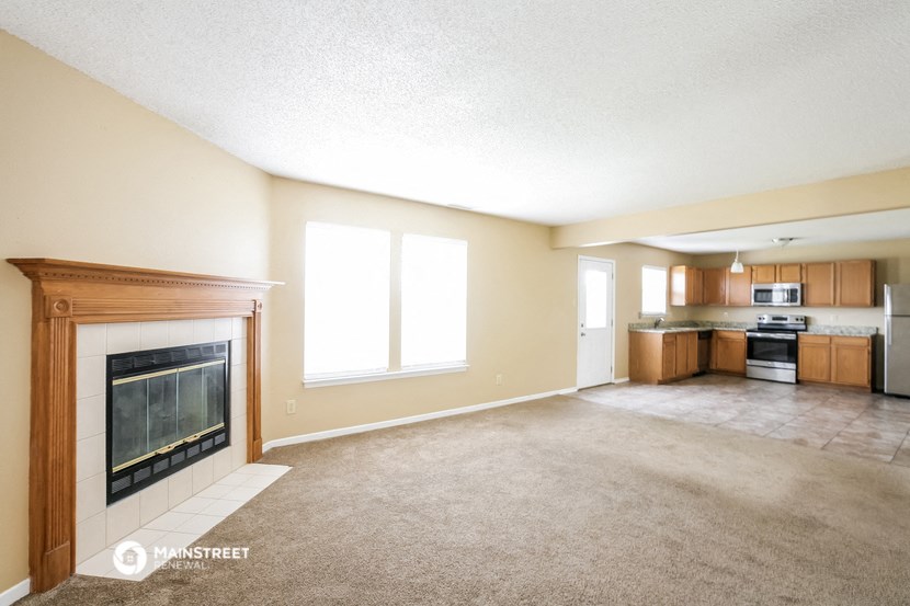 a living room with a fireplace and a kitchen