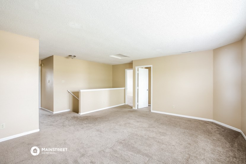 the living room and dining room of an apartment with carpet and white walls