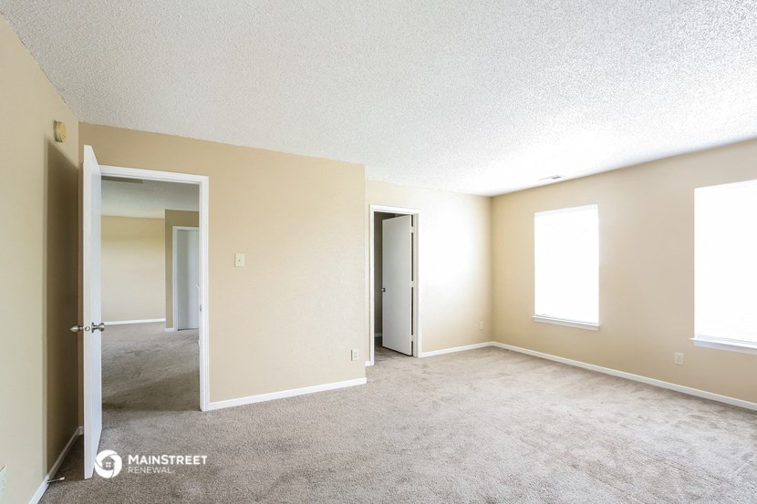 an empty living room with a door to a hallway and a closet
