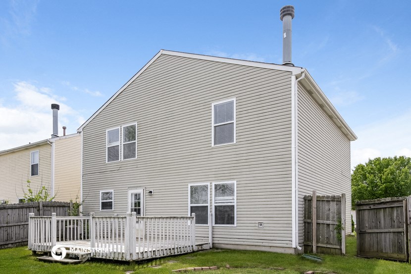 the back of a house with a white fence