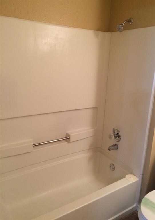 a white bathroom with a white tub and a toilet