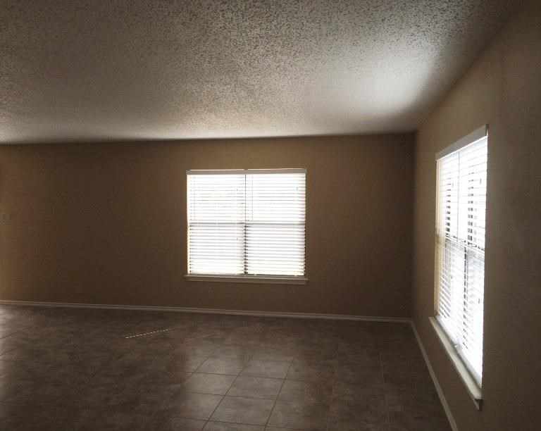an empty room with a window and a tiled floor
