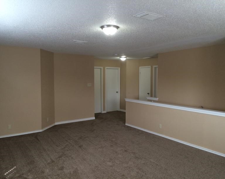 an empty living room with tan carpet and a white wall