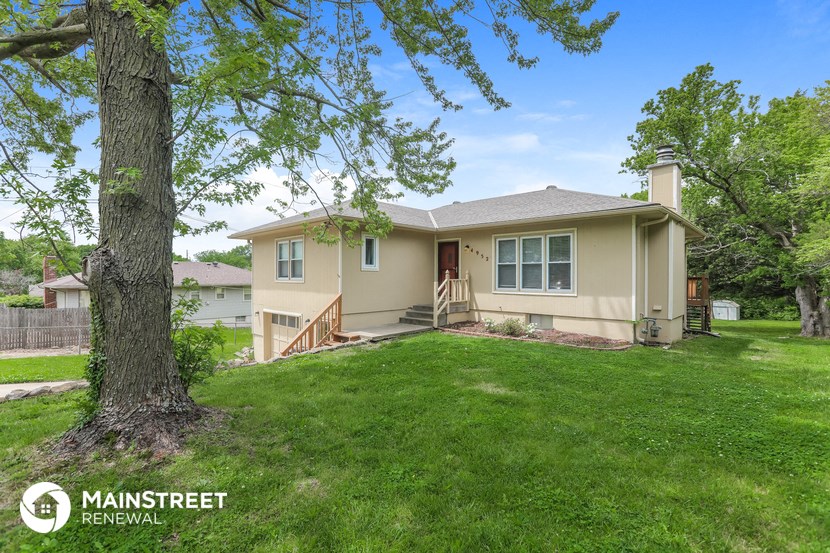 a beige house with a tree in the yard