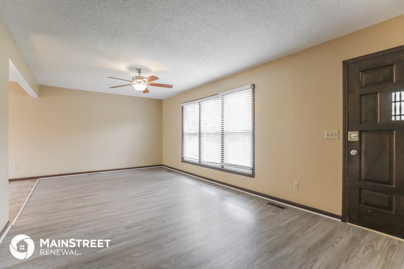the living room of an empty house with a ceiling fan and a window