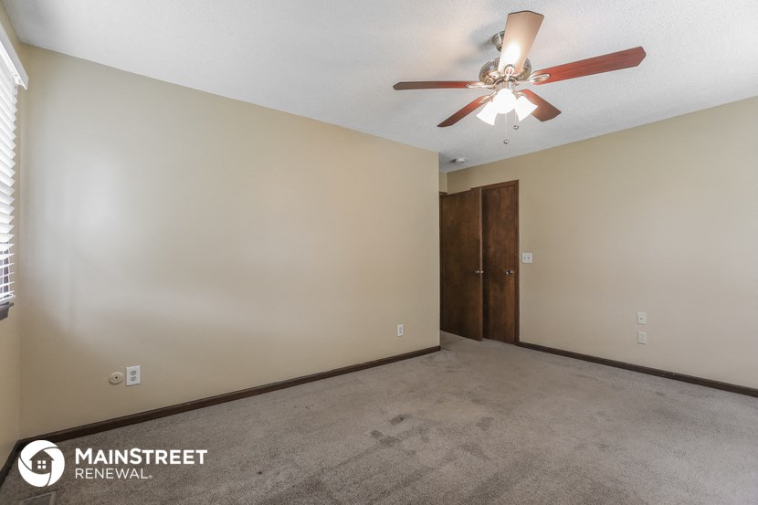 the living room of an empty room with a ceiling fan