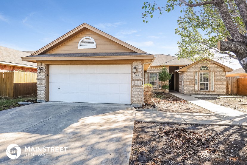 a white garage door in front of a brick house