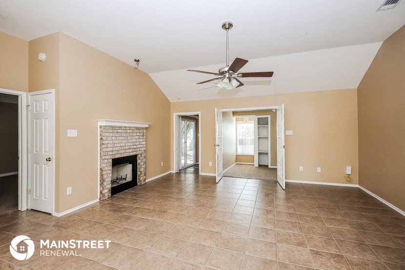a large living room with a fireplace and a ceiling fan