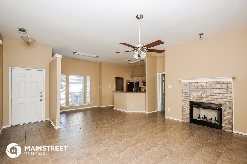 a large living room with a fireplace and a ceiling fan
