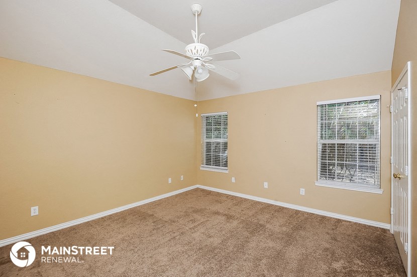 the master bedroom has a carpeted floor and a ceiling fan