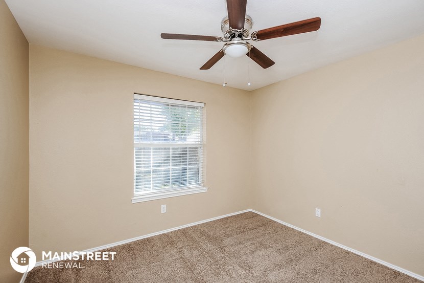 the master bedroom has a ceiling fan and carpet