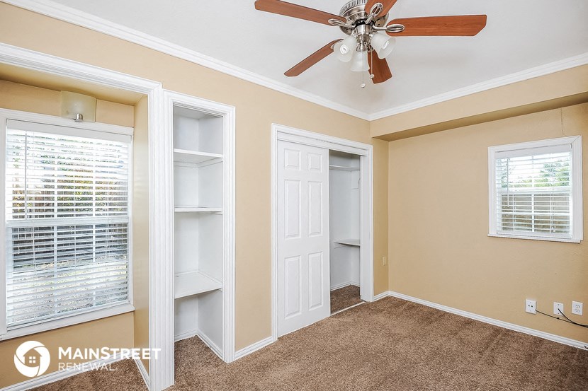 a bedroom with a ceiling fan and a closet with white doors