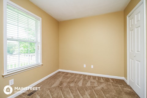 the living room of a new home with carpet and a large window