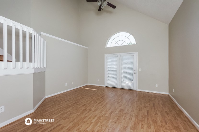 an empty living room with wood flooring and a window